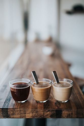 Three glass cups filled with coffee - two with milk and one black