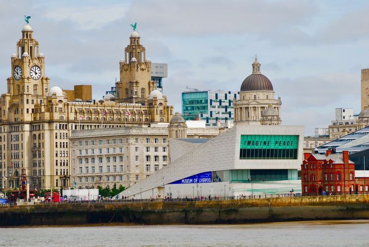 A scene of Liverpool from the river with tourists walking the promenade