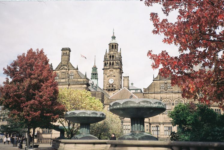 Old buildings and clock tower with red-leaved trees in foreground