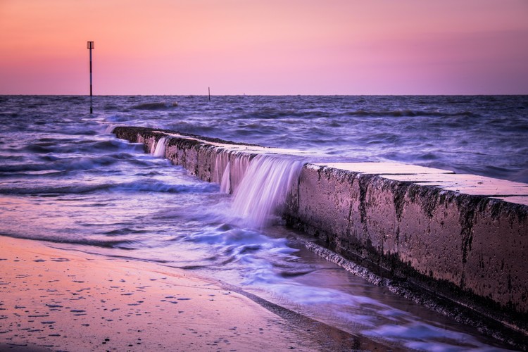 Image courtesy of Simon English Ocean water cascading over stone wall at twilight
